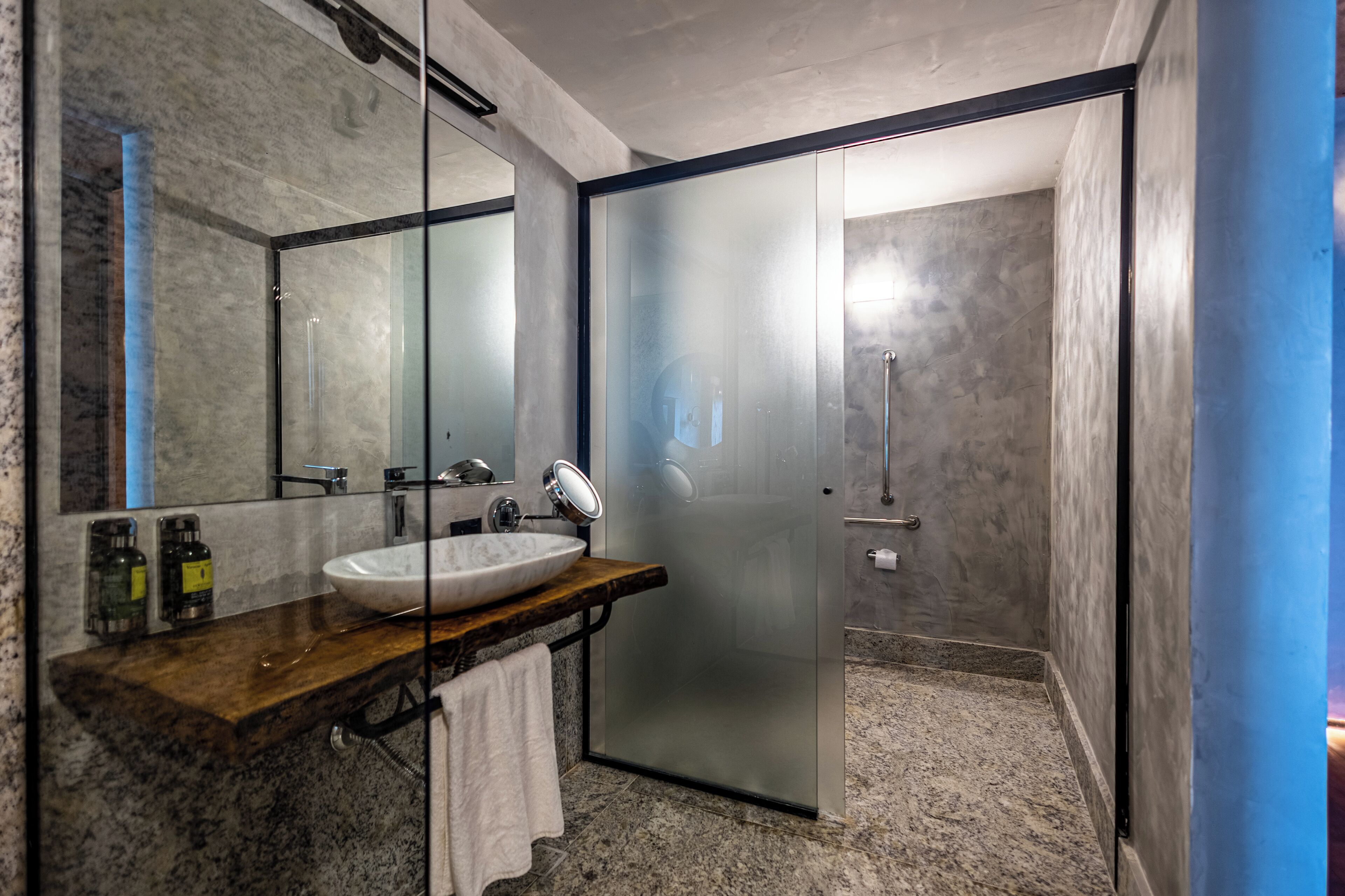 Une salle de bain moderne avec un lavabo en marbre, un grand miroir et une cabine de douche en verre.