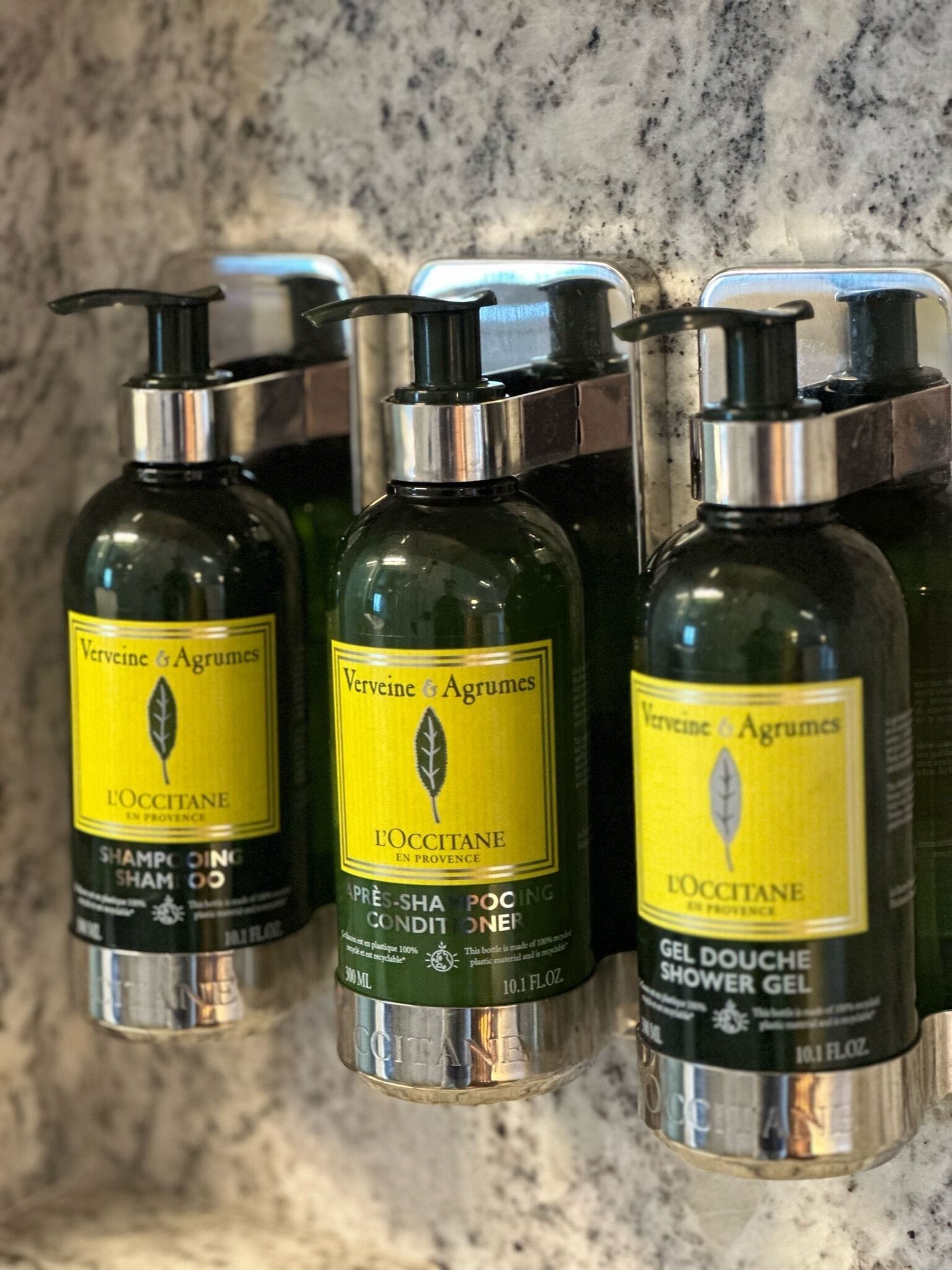 Three bottles of Verveine & Agrumes L'OCCITANE shampoo conditioner and shower gel.