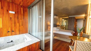 A modern hotel room with a wooden interior, a large bathroom with a marble sink, and a dining area with a table and chairs. - Duke Beach Hotel & SPA Maresias (São Sebastião)