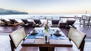 A dining area with a view of the ocean, wooden tables, chairs, and a table set with plates, glasses, and cutlery. - Duke Beach Hotel & SPA Maresias (São Sebastião)