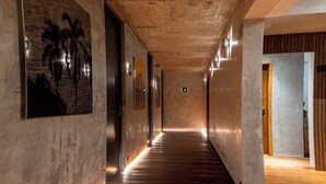 A long, narrow hallway with wooden flooring and walls adorned with framed artwork. - Duke Beach Hotel & SPA Maresias (São Sebastião)