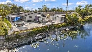 Un quartier résidentiel avec des maisons, une piscine et un petit plan d’eau parsemé de nénuphars.