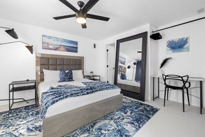Une chambre moderne avec un grand lit, un ventilateur de plafond, un bureau et une chaise.
