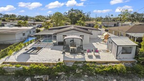 Une propriété résidentielle dotée d’un patio couvert, d’une piscine et d’un espace barbecue.