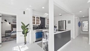 Een moderne keuken met witte kasten, een centraal eiland en een ingebouwde magnetron.