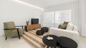 A modern living room with a sofa, armchair, TV, and coffee table.