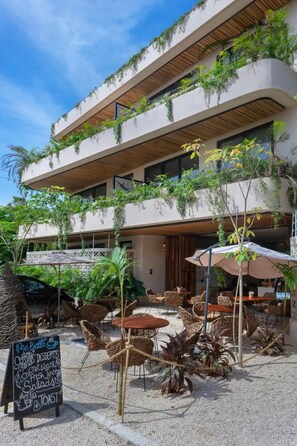 Un café moderno al aire libre con muebles de mimbre y un menú en una pizarra.