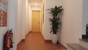 A hallway with a fire extinguisher, a potted plant, and a door at the end. - Thanh Huong 99 Hotel - Noi Bai (Hanoi)
