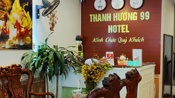 A reception area with a wooden reception desk, a large wall clock, and a sign for Thanh Huong 99 Hotel. - Thanh Huong 99 Hotel - Noi Bai (Hanoi)