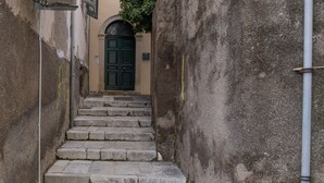A narrow stone staircase leading to a building with a green door. - Captivating 1-bed Apartment in Kerkira (Corfu)