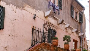A building with a rustic facade, a small balcony with potted plants, and a scooter parked in front. - Captivating 1-bed Apartment in Kerkira (Corfu)