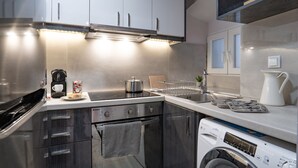 A modern kitchen with stainless steel appliances, a built-in oven, and a washing machine. - Captivating 1-bed Apartment in Kerkira (Corfu)