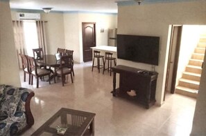 A living room with a dining area, a flat-screen TV, and a staircase. - Peaceful culdesac orchid villa, pool, work ergo (Puerto Plata)