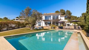 A modern villa with a swimming pool, outdoor seating, and a well-maintained garden.
