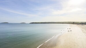 A wide sandy beach with calm waters, a clear sky, and distant hills. - 240 Cae Du (Pwllheli)