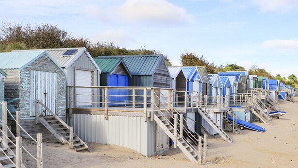 A row of beach huts with wooden staircases leading to the beach. - 240 Cae Du (Pwllheli)