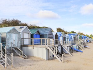 A row of beach huts with wooden staircases leading to the beach.