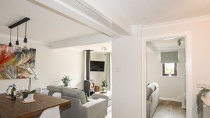 A modern living room with a fireplace, a dining area with a wooden table and chairs, and a gray sofa. - 240 Cae Du (Pwllheli)