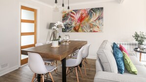 A dining area with a wooden table, white chairs, and a modern pendant light. - 240 Cae Du (Pwllheli)