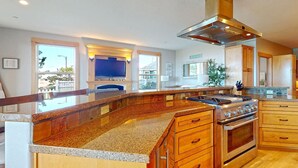 Una cocina amplia con encimeras de granito, estufa de acero inoxidable, gabinetes de madera y una isla grande.