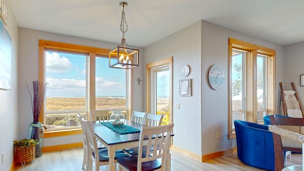 Un comedor amplio con vistas al exterior, ventanas grandes y una lámpara moderna.