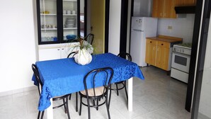 A dining area with a table covered in blue, surrounded by chairs, and a potted plant.