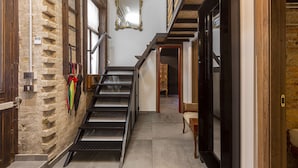 A narrow staircase with a metal railing, a wooden door on the right, and a stone wall on the left. - Luxury In perfect Downtown, specially designed for groups (Budapest)