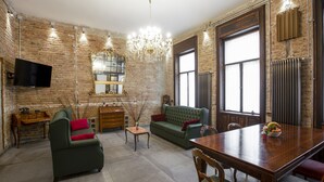 A spacious living room with a green sofa, a wooden dining table, and a chandelier. - Luxury In perfect Downtown, specially designed for groups (Budapest)