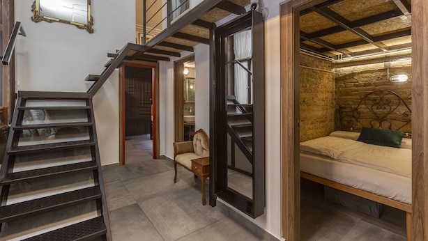 A bedroom with a bed, a chair, a staircase, and a mirror. - Luxury In perfect Downtown, specially designed for groups (Budapest)