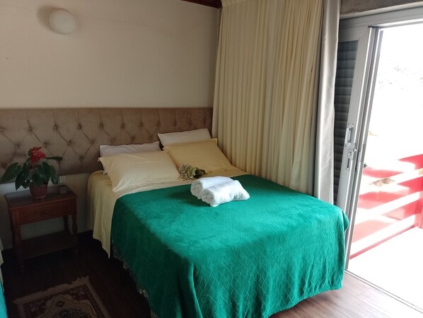 A neatly made bed with a green bedspread, a potted plant, and a bedside table. - RECANTO VIRGINIA BRACELLI (Campos do Jordão)