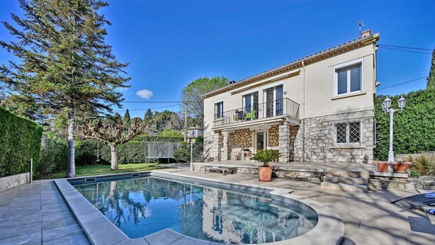 Una casa de dos pisos con fachada de piedra, piscina y zona de patio.