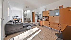 Una sala de estar moderna con un sofá gris, un mueble de madera y una escalera que lleva a otra habitación.