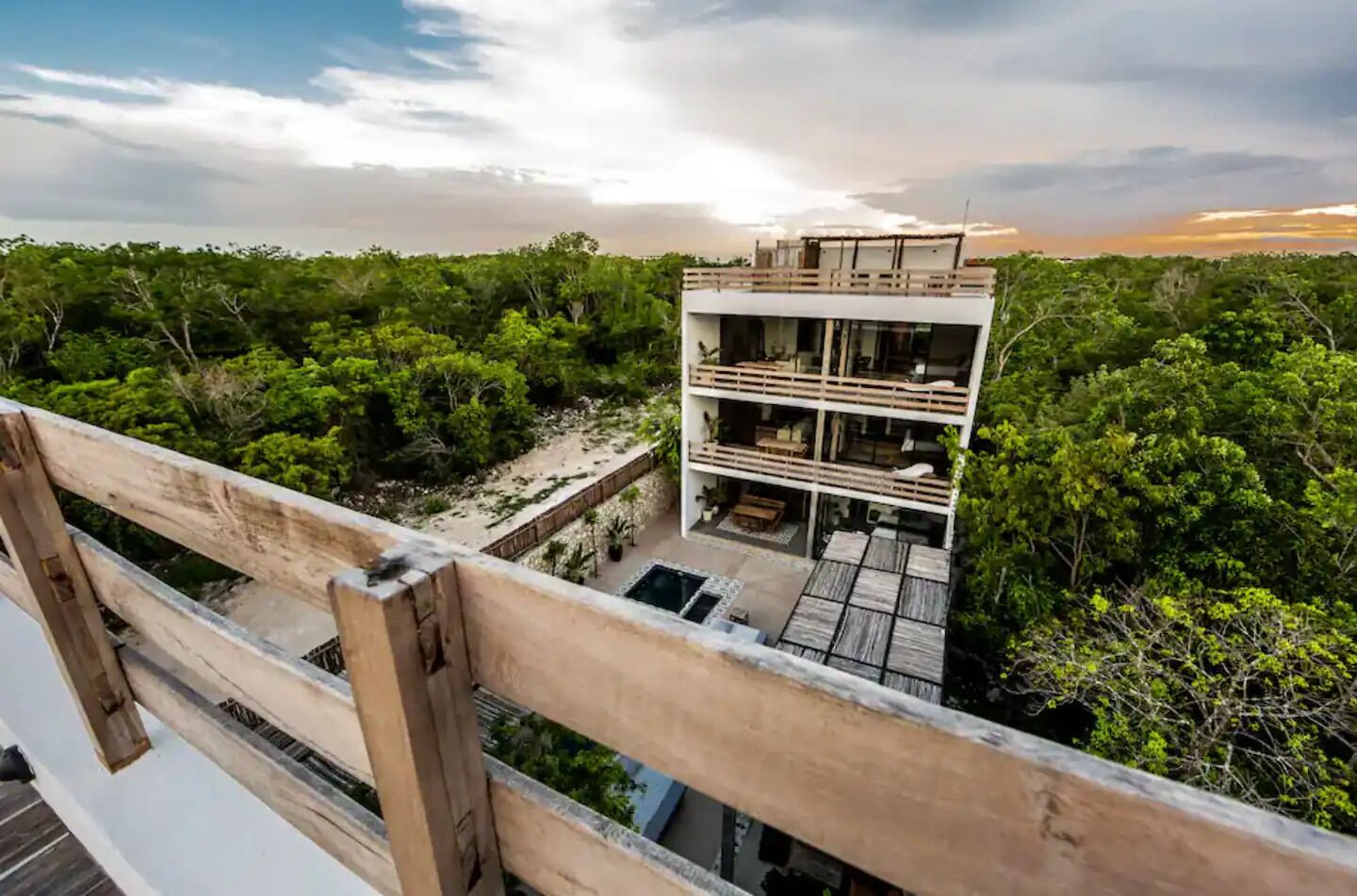 A modern multi-story building with a flat roof, surrounded by dense greenery.