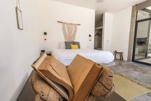 Quarto moderno com uma cama grande, uma escultura de madeira e vista para o exterior.