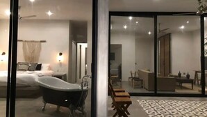 Une chambre à coucher moderne avec une grande baignoire, un lit et une table de chevet.