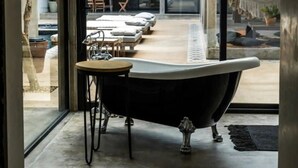Une salle de bain moderne avec une baignoire sur pieds, une petite table et un tapis.