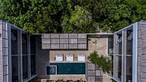 Un espace piscine extérieur moderne, doté d’une piscine rectangulaire, entourée de mobilier de jardin en bois et de chaises longues.