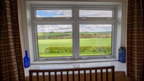 A room with a large window overlooking a green landscape. - Wild Rose in rural location with lovely views on a working farm with walks (Jedburgh)