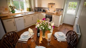 A modern kitchen with a dining area set for a meal. - Wild Rose in rural location with lovely views on a working farm with walks (Jedburgh)