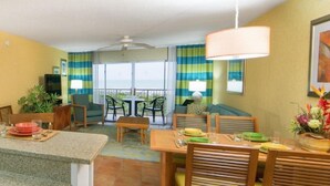 A modern kitchen with granite countertops, a sink, and a dining area with a table and chairs.