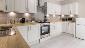 Une cuisine moderne avec des armoires blanches, un évier en acier inoxydable, une cuisinière et un four à micro-ondes.