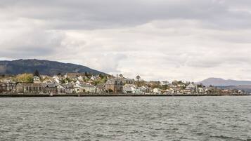 A coastal town with houses along the waterfront, a harbor, and hills in the background.