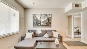 Ein modernes Wohnzimmer mit einem Ecksofa, einem Couchtisch und einem großen Fenster.