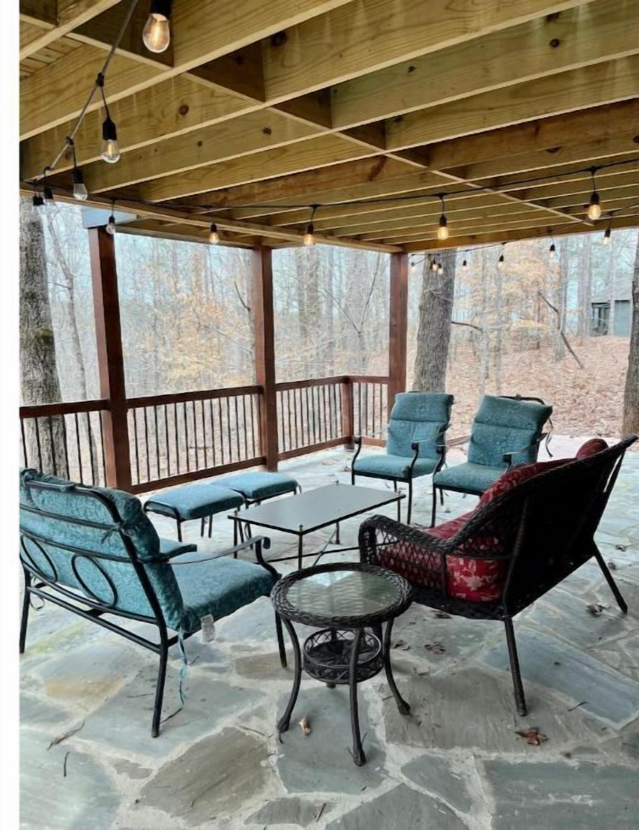 Une terrasse extérieure avec un sol en pierre, une table ronde et quatre chaises avec des coussins.
