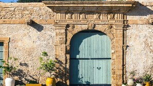 Um edifício de pedra com uma grande porta em arco, plantas em vasos e um arco de pedra decorativo.