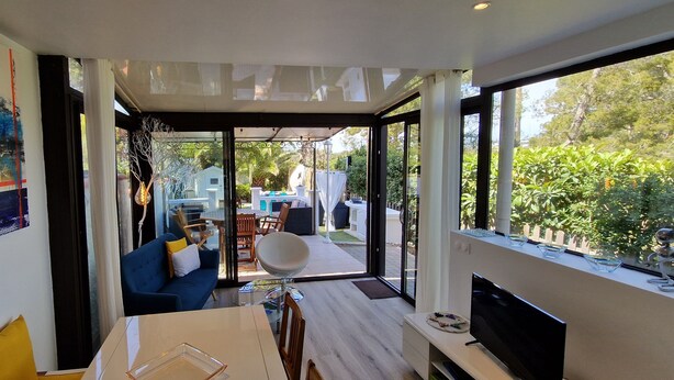 A modern interior with a blue sofa, a dining table, and a TV.