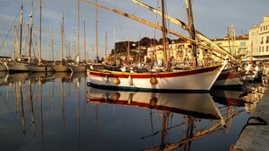 A marina with multiple boats docked, a building with a sign reading "HOTEL" in the background, and a clear sky.