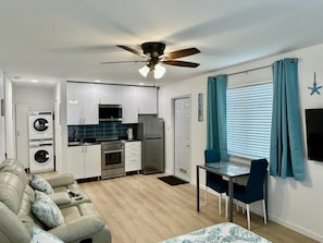 Cozy living space with a kitchenette, dining table, sofa, and washing machine.