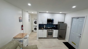 A modern kitchen with stainless steel appliances, a washing machine, and a dining area with a table and chairs.