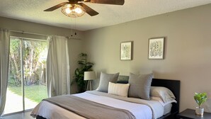 A bedroom with a bed, a nightstand, a ceiling fan, a window with curtains, and a plant. - Cozy Suburban Home with huge backyard and pool! Welcome! (Miami)